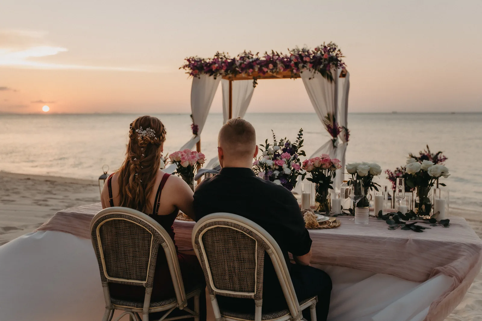 A private table set on the sand at sunset
